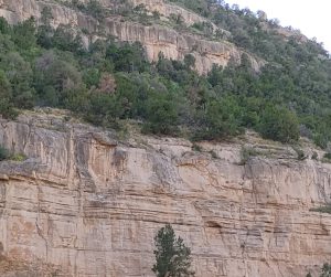 A massive, solid rock mountain with a prominent giant yellow rock formation standing tall and firm under the sky in New Mexico.