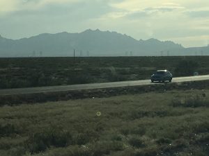 A highway ahead with a massive mountain visible in the distance on the left side under the sky.