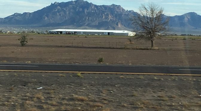 A beautiful open field with a soft line of mountains sitting along the distant horizon under a calm sky.