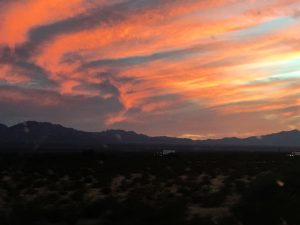 A beautiful mountain range underneath a gorgeous orange and yellow sunset sky.