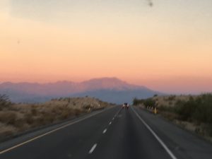 A peaceful dusk horizon over a silent mountain range with fading golden twilight light reflecting off dark, soft mountain silhouettes.