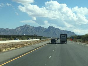 A striking photograph of a beautiful, towering mountain range stretching across the horizon ahead on an open West Coast highway drive.