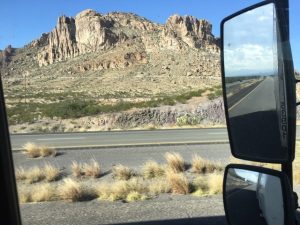 An outstanding photograph of a giant, massive rock wall looming huge on the left side of an open West Coast highway drive.