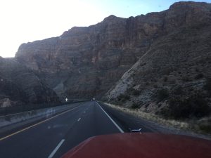 A striking West Coast drive looking down an open road enclosed on both sides by rugged stone mountains.