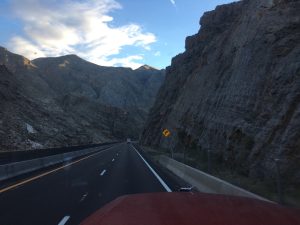 A two-lane mountain highway curving smoothly between massive solid rock mountains on both sides