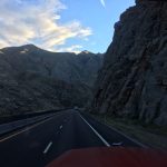 A striking view looking down an open road enclosed on both sides by towering, solid rock mountains under a framing sky