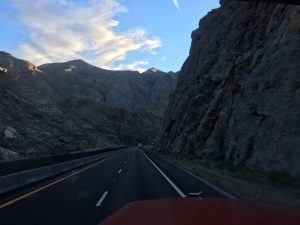 A highway ahead enclosed by solid rock mountains on either side under the sky.
