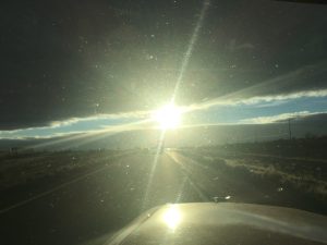 An awesome photograph taken from inside a vehicle showing a driver with a long, bright line of sunlight streaming through the window, catching his reflection in the glass.