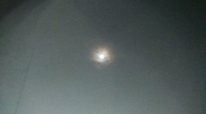A close-up nighttime photograph of a tiny but incredibly bright moon positioned inside the center of a giant, glowing sphere anomaly.