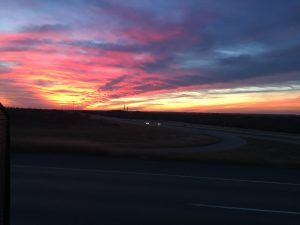 A beautiful landscape photograph taken at dusk showing a brilliant sunset with vibrant pink gold and blue clouds stretching across the sky.