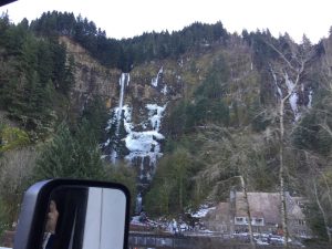 A photograph of a parked 18-wheeler truck resting next to a massive rock mountain.