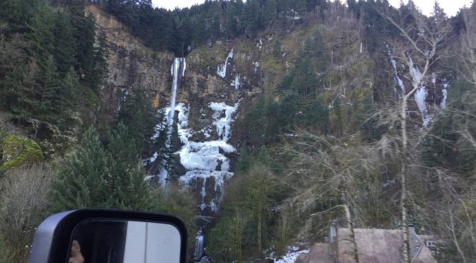 • A photograph of a parked 18-wheeler truck resting next to a massive rock mountain.