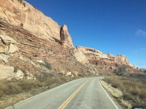  A striking landscape photograph looking down a curved asphalt highway that winds gracefully between two massive, towering rock mountains.