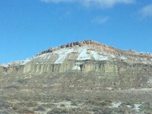 A beautiful photograph of a massive mountain made entirely of solid, bone-colored rock, standing completely bare with no trees or fields in sight