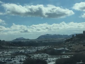  A beautiful photograph showing majestic mountain peaks underneath soft rolling clouds with open terrain stretching out into the distance.