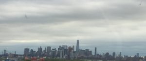 A wide photograph of the New York City skyline filled with towering high-rise buildings and skyscrapers under a clear sky.
