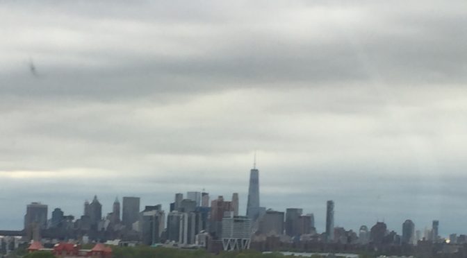 A wide photograph of the New York City skyline filled with towering high-rise buildings and skyscrapers under a clear sky.