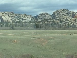 A high-quality, dramatic landscape photograph of a rugged rock mountain range under dark, swirling stormy skies, highlighting a unique and beautiful natural rock formation in sharp focus.