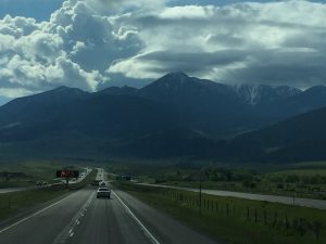 A dark mountain peak silhouetted against glowing white clouds with sunlight breaking from behind.