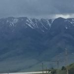 View from the front of an 18-wheeler truck driving toward distant mountains under a dark, dramatic evening sky.