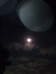 A luminous full moon shining brightly in the night sky over a backyard in McAllen, Texas, with a massive, radiant atmospheric sphere glowing softly on the side.