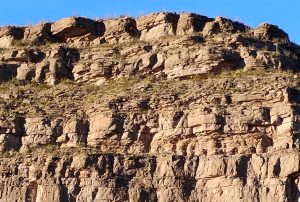 A massive rugged mountain of pure solid rock rising under a wide clear sky in New Mexico.